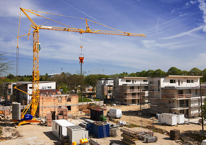 A self-erecting Potain tower crane at a construction site